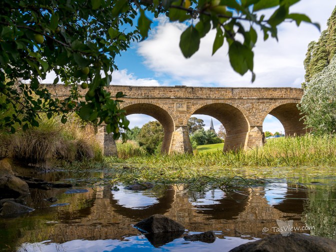 Richmond Bridge, low shot close to water with church spire apearing though an arch.